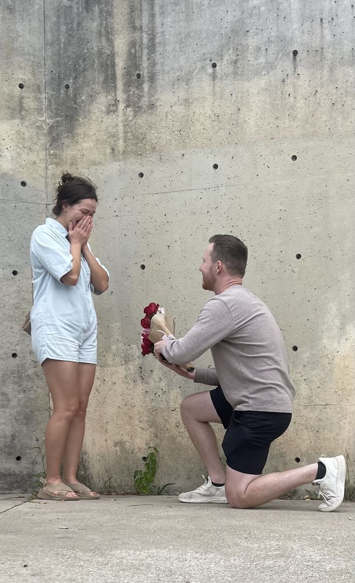 Mitchell on one knee with a red bouquet